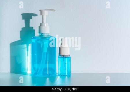 Flaschen von blauen Anti-septischen Alkohol Hand Gel und Spray auf weißem Tisch und Gießen blauen Schatten auf weißen Wand Hintergrund, Produkt für saubere und Sicherheit d Stockfoto