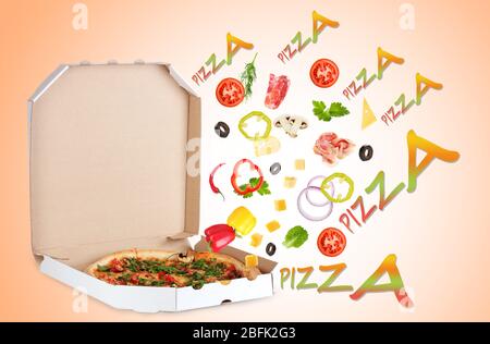 Leckere Pizza in Pizzabox und Zutaten auf farbigem Hintergrund Stockfoto