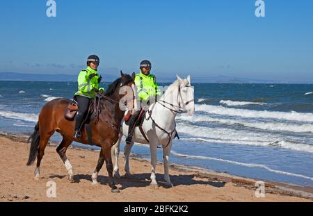 Portobello Beach, Edinburgh, Schottland. April 2020. Freundliche berittene Polizei mit Pferden namens Logie und Edinburgh die weiße, ihre tägliche Patrouille der Promenade und Strand bei hellem sonnigem Wetter weniger Menschen als gestern, als die Coronavirus Lockdown weiter, Auf der Promenade waren allerdings Radfahrer unterwegs, was mehr war als am Strand, obwohl der Sandstrand für Wanderer leichter sein kann, sich selbst zu isolieren. Temperatur von 10 Grad bei einem ENE-Wind von 17km/h potenzielle Böe von 33km/h. Quelle: Arch White/Alamy Live News. Stockfoto