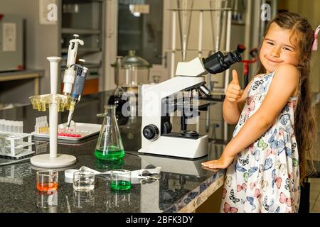 Alle Hände an Bord, kleine Helferin eine Ärztin mit Daumen hoch, als sie Impfung oder Heilung für Coronavirus oder Covid 19 fand, positives Konzeptfoto Stockfoto