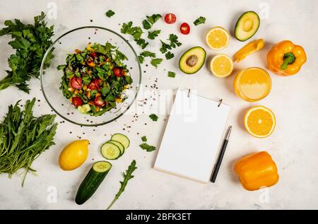 Saftiger vegetarischer Salat zu Hause für einen schnellen Happen. Draufsicht. Ein Buch zum Schreiben von Rezepten liegt auf dem Tisch. Platz für Text kopieren Stockfoto