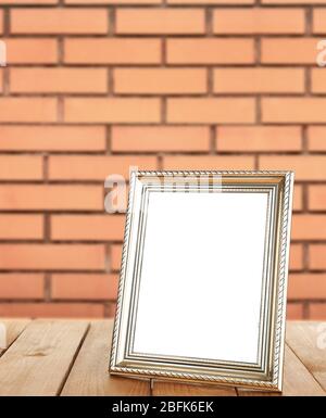 Bilderrahmen auf Tisch auf Backstein Wand Hintergrund stehend Stockfoto