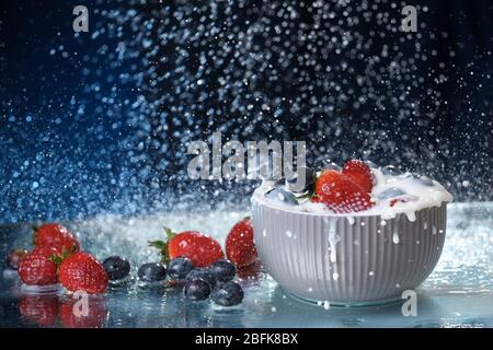 Milch spritzt aus der Nähe von fallenden Beeren in einem grauen Teller Milch. Erdbeeren und Heidelbeeren Multivitamin-Cocktail. Gesunde Ernährung. Bio-Lebensmittel. Wasser Stockfoto