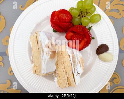 Dessertplatte mit Karamell-Eiskuchen, roten Rose Erdbeeren, grünen Trauben und Pralinen in Herzform Stockfoto