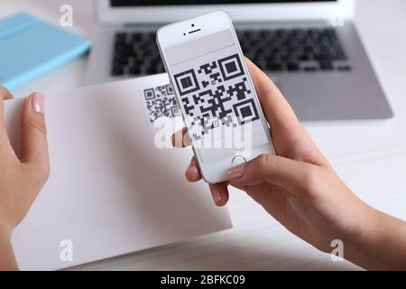 Frau scannt Gutschein-Code mit Handy aus nächster Nähe Stockfoto