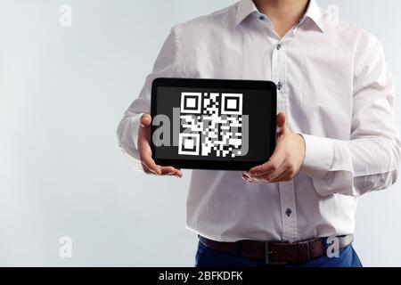 Geschäftsmann hält Tablet-PC mit QR-Code auf dem Bildschirm Stockfoto