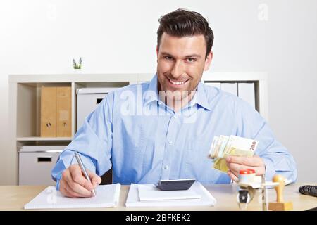 Lachender Geschäftsmann mit Banknoten im Büro Stockfoto