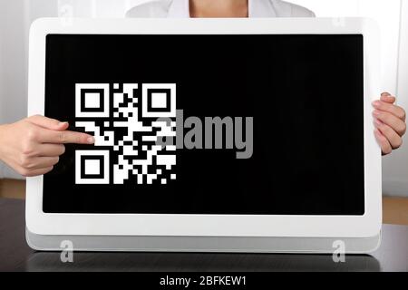 Hände, die den Tablet-PC mit QR-Code auf dem Bildschirm halten Stockfoto