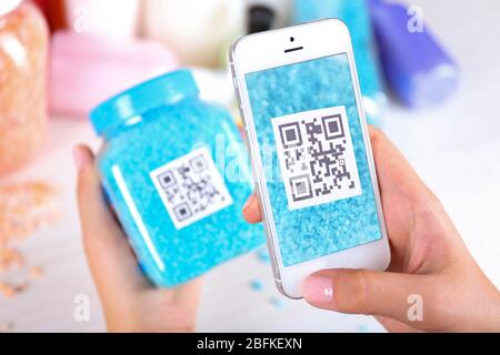 Frau scannt Gutschein-Code mit Handy aus nächster Nähe Stockfoto