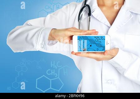 Junger Arzt hält Smartphone mit DNA-Molekül auf dem Bildschirm Stockfoto