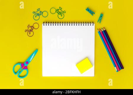 Notizbuch zum Zeichnen oder Schreiben auf gelbem Hintergrund mit verschiedenen Schreibwaren-Accessoires. Stockfoto