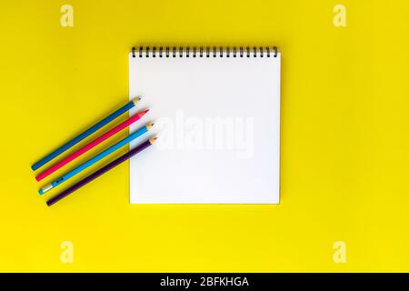 Notizbuch zum Zeichnen oder Schreiben auf gelbem Hintergrund mit verschiedenen Schreibwaren-Accessoires. Stockfoto