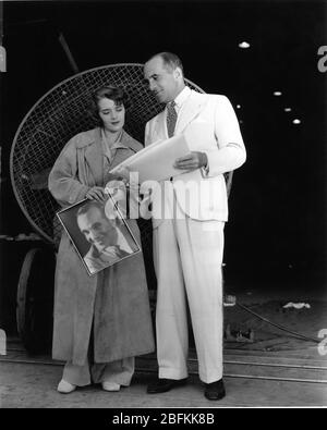 AL JOLSON zeigt seiner Frau RUBY KEELER Fotos von sich am Set Candid auf Warner Bros. Studio Lot Juni 1934 Warner Bros. Publicity Stockfoto