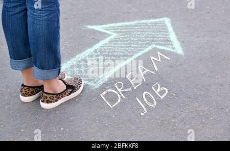 Traumjob Konzept. Weibliche Füße und Zeichnungspfeil auf Bürgersteig Hintergrund Stockfoto