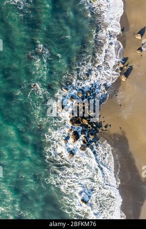 Strandszene von oben mit bunten Wellen, die auf eine Gruppe von Felsen an der Küste von Oregon stürzen Stockfoto