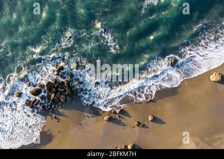 Strandszene von oben mit bunten Wellen, die auf eine Gruppe von Felsen an der Küste von Oregon stürzen Stockfoto