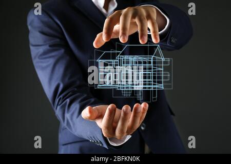 Immobilienangebot. Geschäftsmann hält ein künstliches Modell des Hauses Stockfoto