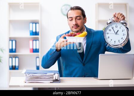 Junge Angestellte, die am Arbeitsplatz frühstücken Stockfoto