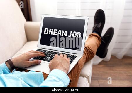 Traumjob Konzept. Mann, der mit einem Laptop auf dem Sofa im Zimmer arbeitet Stockfoto