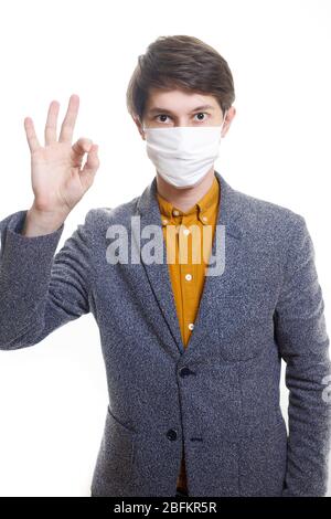 Stoppen Sie die Infektion EIN gesunder Mann zeigt die OK-Geste. Auf dem Foto trägt der Mann eine Schutzmaske gegen Infektionskrankheiten und Grippe. Der Nachteil Stockfoto