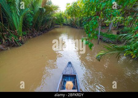 Bootstour durch das Mekong-Delta, Ben Tre, Südvietnam. Holzboot auf Kreuzfahrt im Wasserkanal durch Kokospalmenplantage. Stockfoto