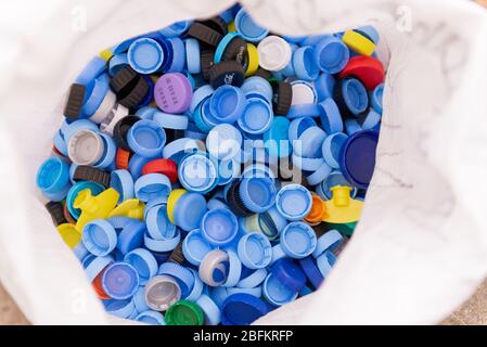 Plastikkappen in einer Tasche. Viele Plastikflaschen-Kappen. Die Kampagne für die getrennte Abfallsammlung. Stockfoto