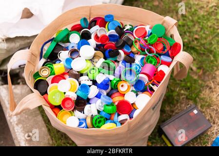 Plastikkappen in einer Tasche. Viele Plastikflaschen-Kappen. Die Kampagne für die getrennte Abfallsammlung. Stockfoto