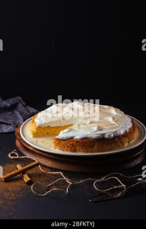 Hausgemachte Zubereitung einer drei-Milch-Tarte. Das Bild ist auf einem dunklen Hintergrund und rustikalen Bretter gemacht. Venezolanischer Kuchen Stockfoto