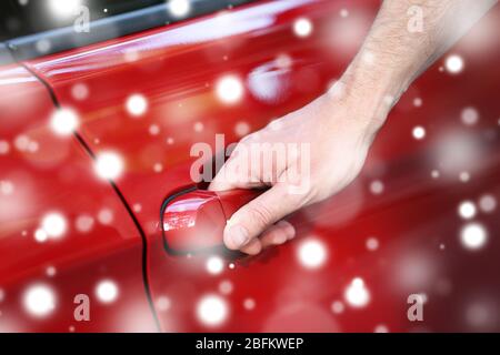 Männliche Hand hält die Tür Griff des roten Autos über Schnee-Effekt Stockfoto