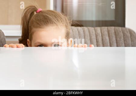 Kleines Mädchen, das von hinter Tisch aus guckt, Kopierer Stockfoto