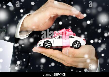 Mann hält Modell des Autos in seinen Händen über Schnee-Effekt Stockfoto