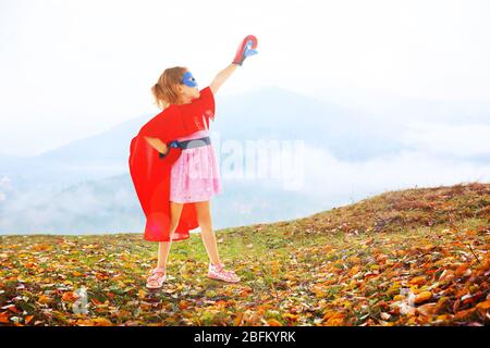 Superhelden kleines Mädchen posiert in Boxhandschuhe auf Bergen Hintergrund Stockfoto