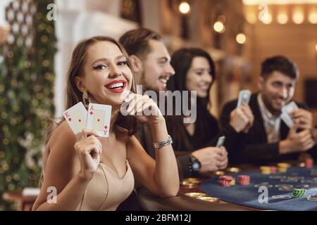 Mädchen mit Karten in ihren Händen lächelt Winning Poker in einem Casino. Stockfoto