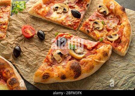 Pizzaböden mit Mozzarella-Käse, Schinken, Pilzen und Tomatensauce. Ein Stück frische italienische klassische Original-Pizza Stockfoto