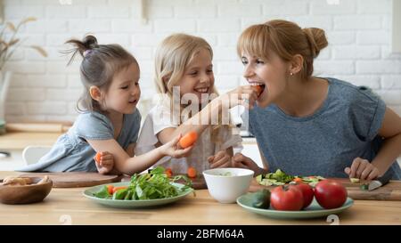 Fürsorgliche Tochter füttern Mutter Unterricht kleine Kinder. Stockfoto