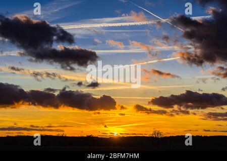 Sonnenuntergang, Wolken und Flugzeug-Kondensstreifen - Zentralfrankreich. Stockfoto