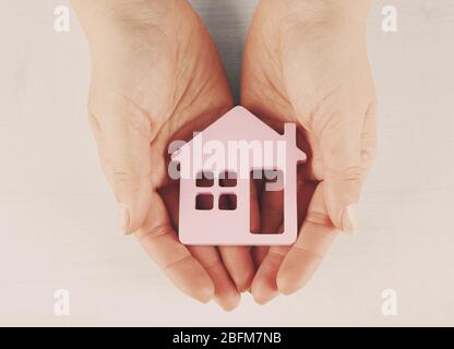 Weibliche Hände mit Modell des Hauses auf hellem Hintergrund Stockfoto