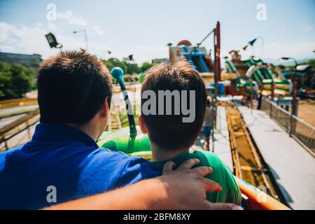 Teenager und sein kleiner Bruder fahren auf einer bunten Achterbahn Stockfoto