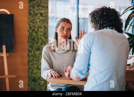 Junger Mann und Frau lächeln und unterhalten sich an der Kaffeebar angenehm Stockfoto