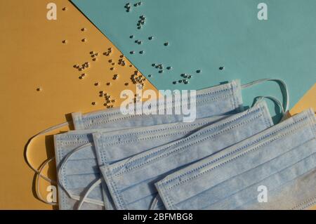 Viele medizinische Masken, silberne Perlen auf dem gelben und blauen Hintergrund, Farbe der ukrainischen Flagge. Konzeptionelles Foto als Schutz vor verschiedenen Arten von vi Stockfoto