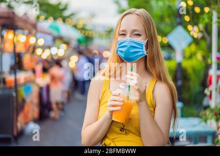 Frau in medizinischer Maske, die Orangensaft auf dem asiatischen Markt trinkt Touristen fürchten das 2019-ncov-Virus. Medizinische maskierte Touristen Stockfoto