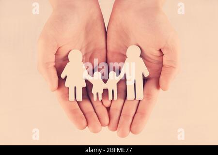 Weibliche Hände mit Familienmodell auf hellem Hintergrund, Nahaufnahme Stockfoto