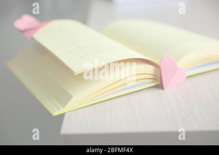 Buch und Origami-Herz als Lesezeichen auf Holztisch Stockfoto