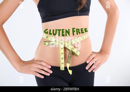 Junge schlanke Frau, die ihre Taille misst und Text Glutenfrei auf ihrem Körper isoliert auf weiß Stockfoto