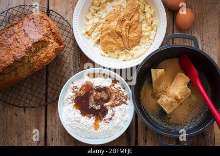 Bananenbrot und Zutaten: Butter, brauner Zucker, Ahornsirup, Mehl, zerdrückte Bananen, Eier, Erdnussbutter Stockfoto