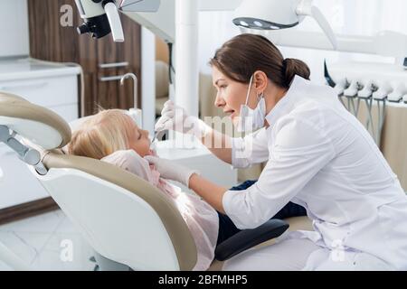 Eine junge Zahnärztin, die eine gründliche Untersuchung der Zähne ihres Patienten durchführt. Stockfoto