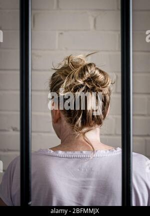 Eine weibliche Gefangene hinter Gittern in einem Frauengefängnis. Bild nach Modell gestellt. Stockfoto