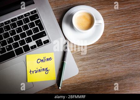 Online-Schulung auf Haftnotiz, Laptop und Tasse Kaffee auf dem Tisch, Draufsicht Stockfoto