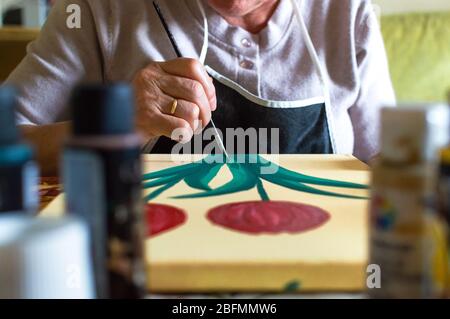 Vorderansicht der alten Frau, die zu Hause ein Bild malt. Kunst im Alter und Freizeit zu Hause. Stockfoto