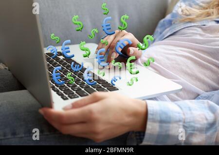 Geld verdienen online Konzept. Frau, die einen Laptop mit Dollar- und Euroscheinen benutzt, die draußen heraukommen, drinnen Stockfoto
